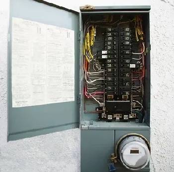 A grey electrical box with wires and a round circular object.